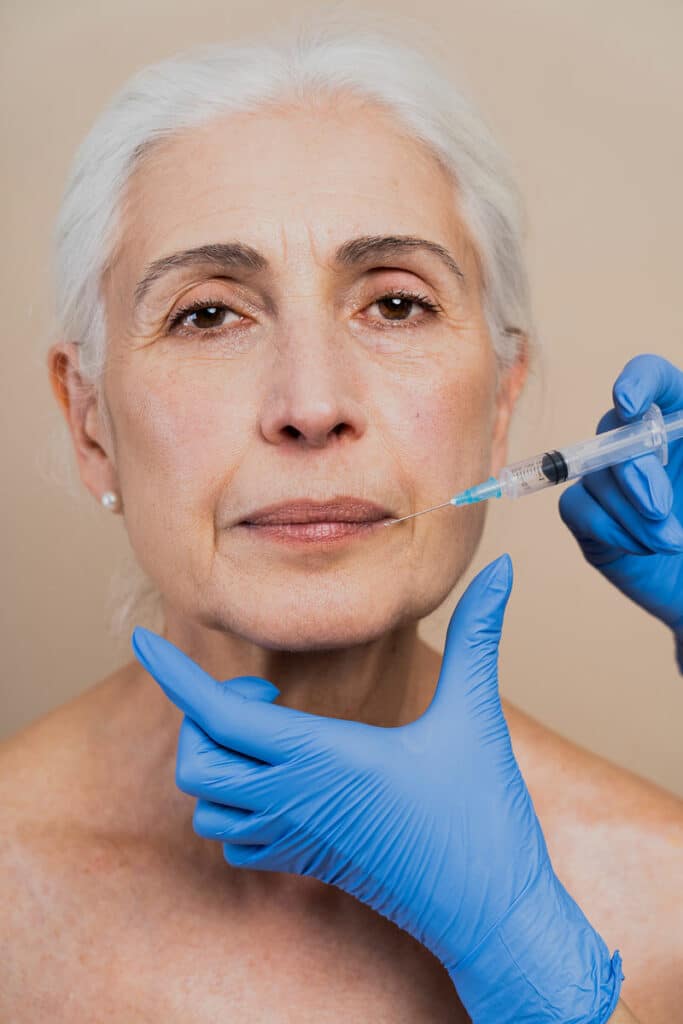 Older woman receiving RHA Collection Filler injection in her cheek.