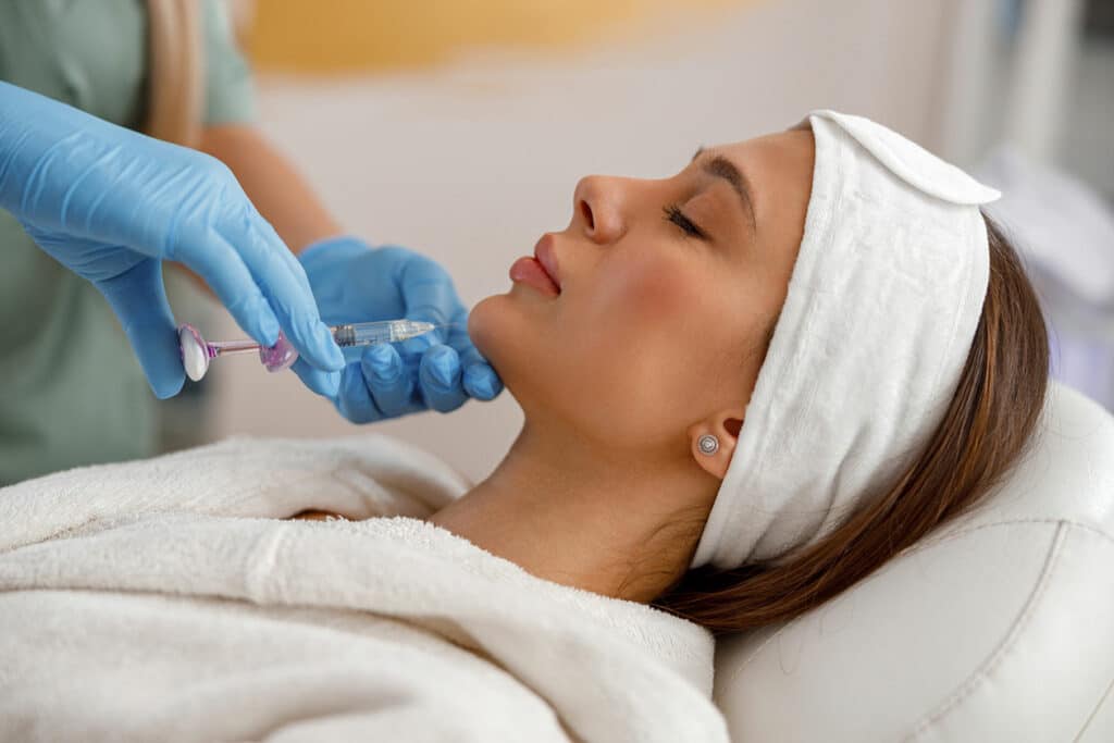 Side view of-young-woman getting kybella injection in her chin.